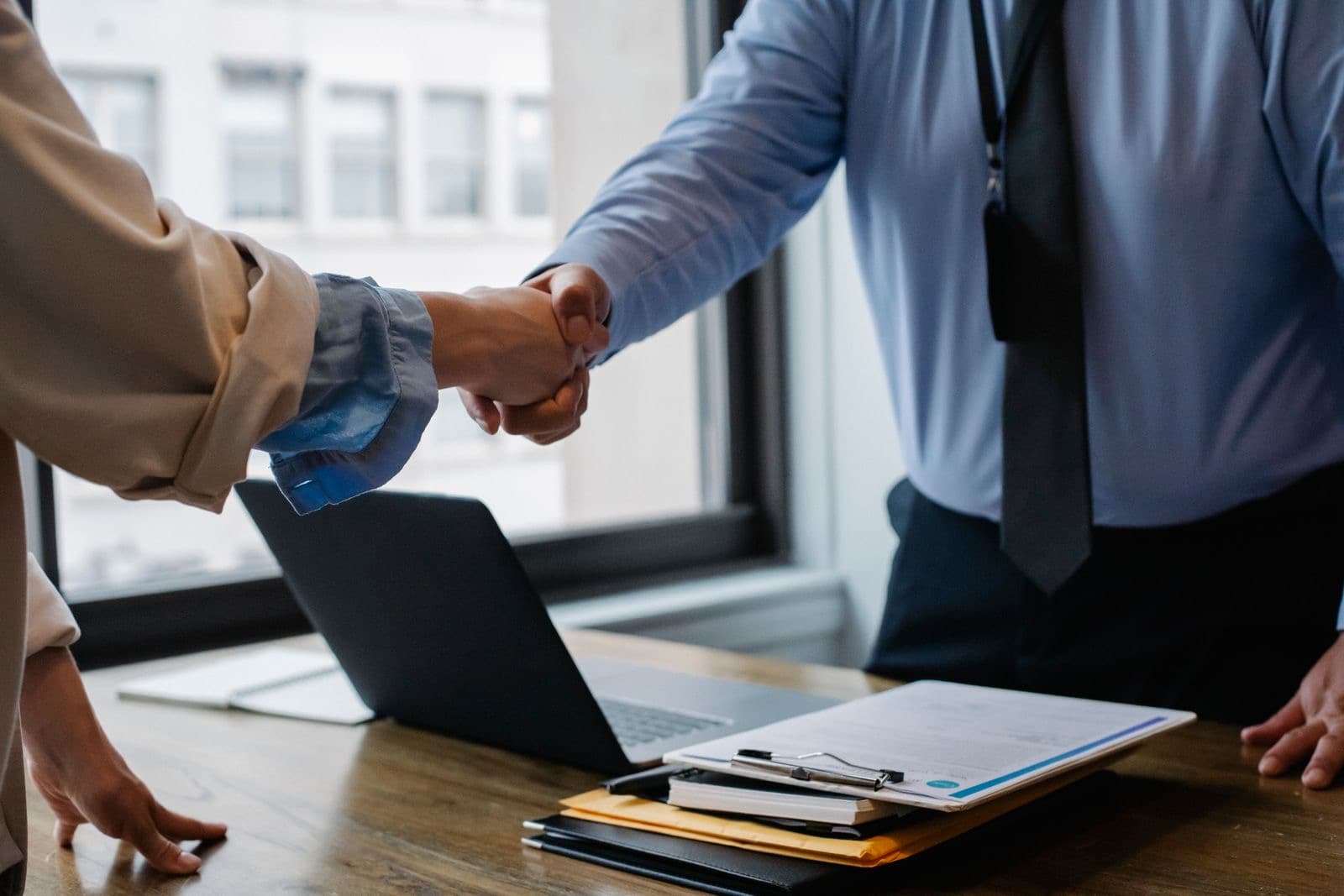 Two colleagues shaking hands across a desk