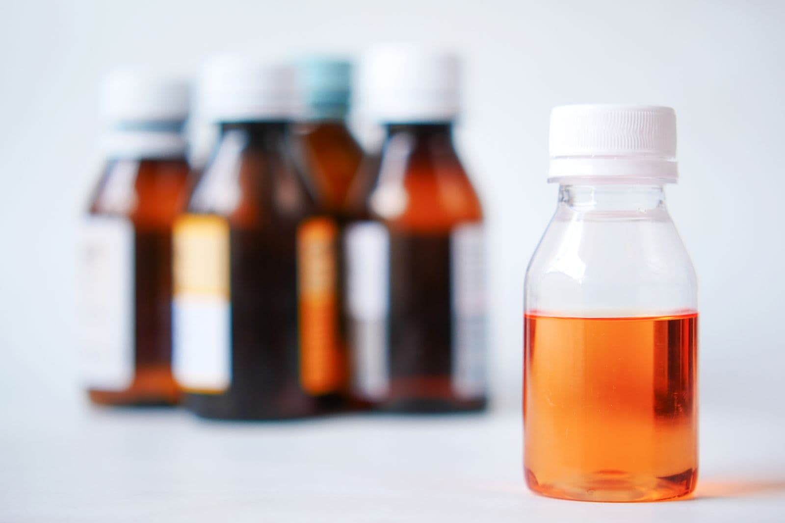 Bottles of oral liquid medicine, one clear bottle in focus